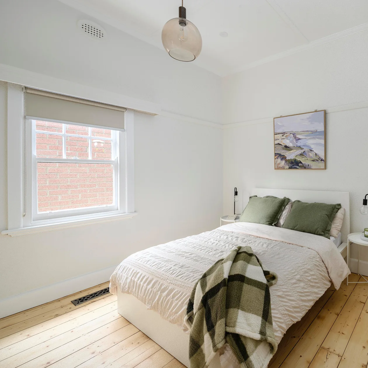 Bright bedroom with a smoked glass pendant light and timber floorboards