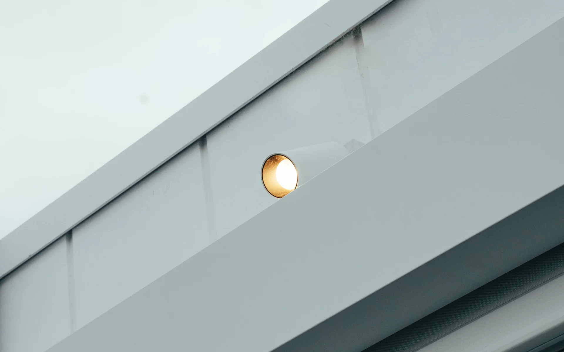 Warm downlight glowing under the white eave of a home
