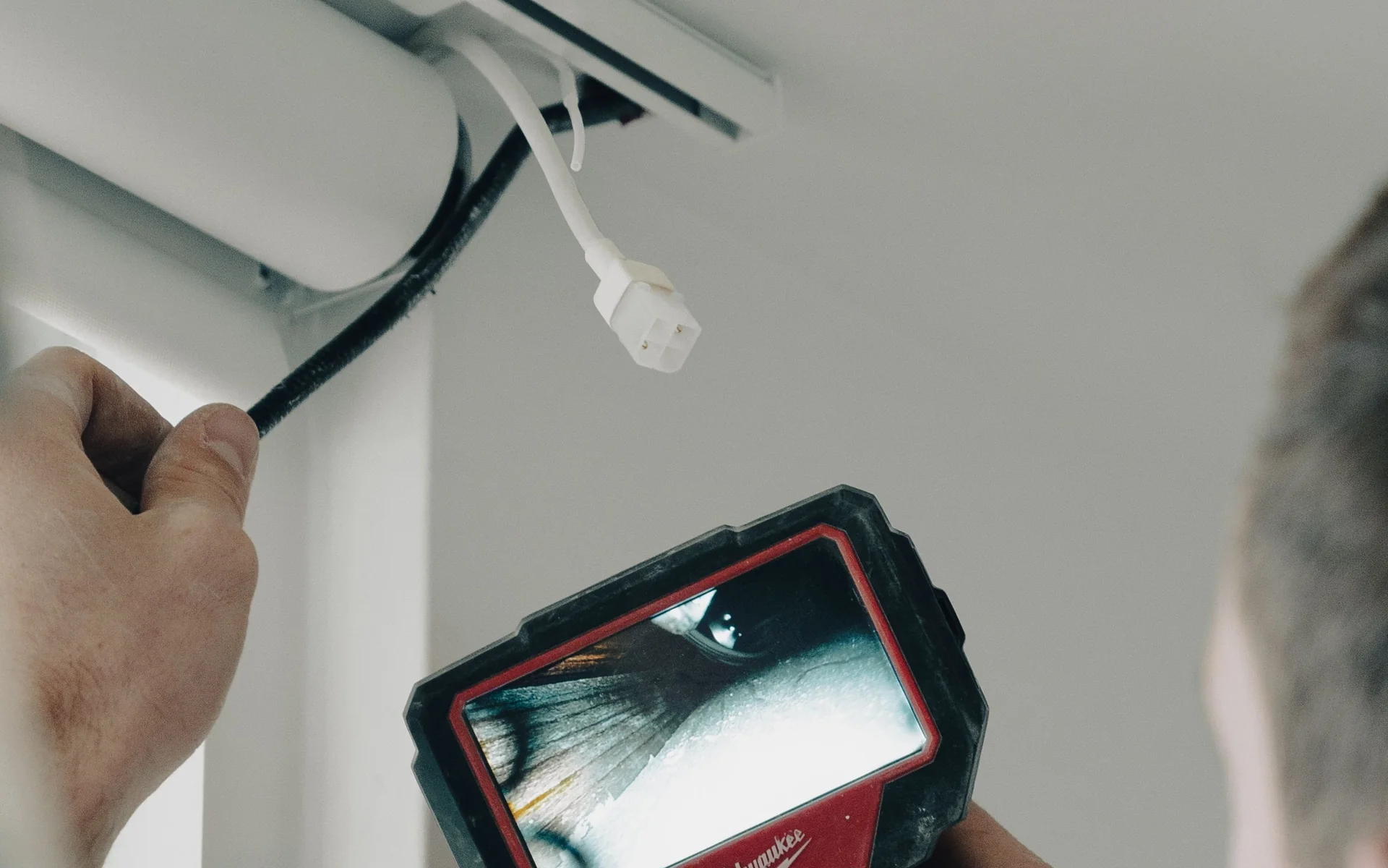 Electrician using an inspection camera to look behind a fitting near the ceiling