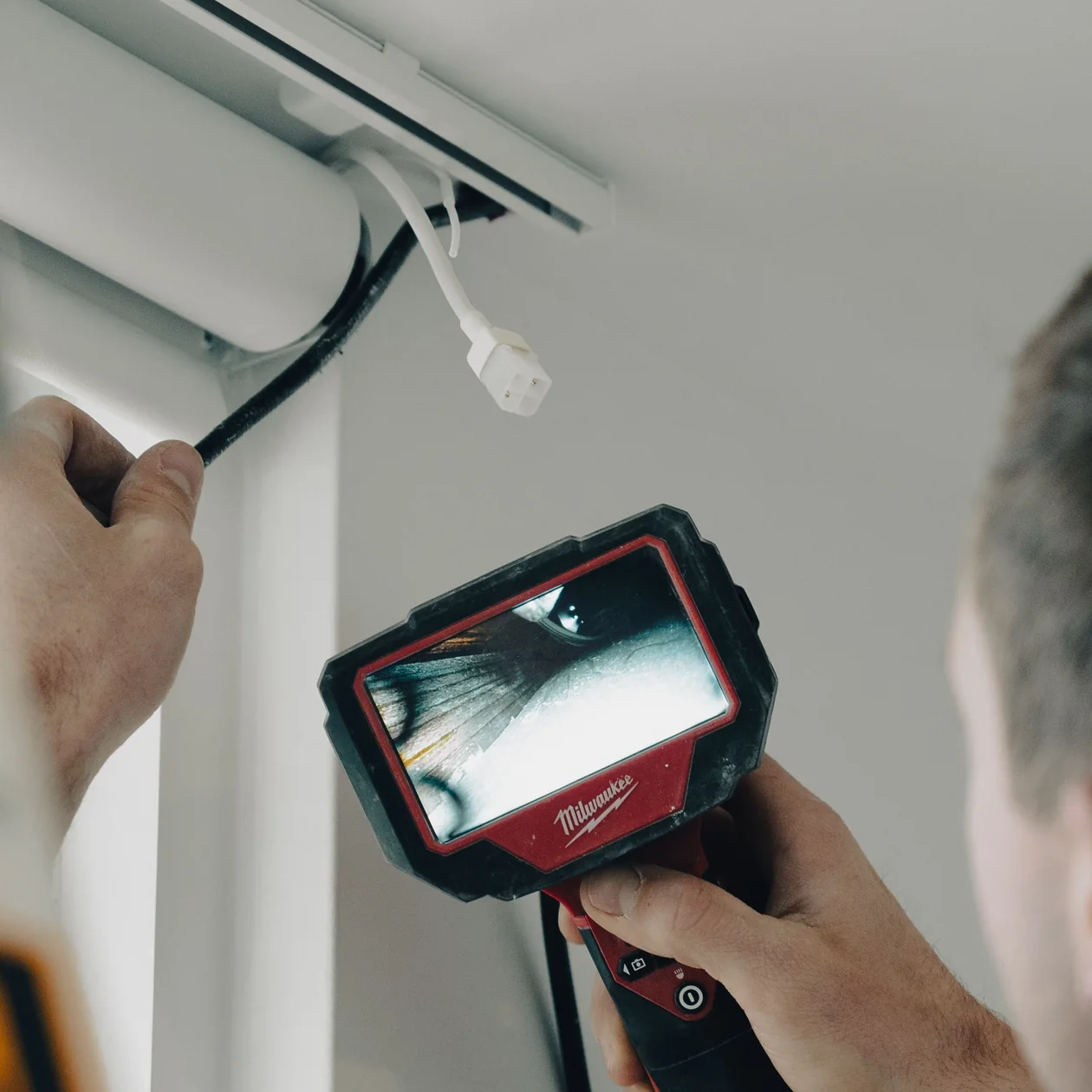 Electrician using an inspection camera near a ceiling track