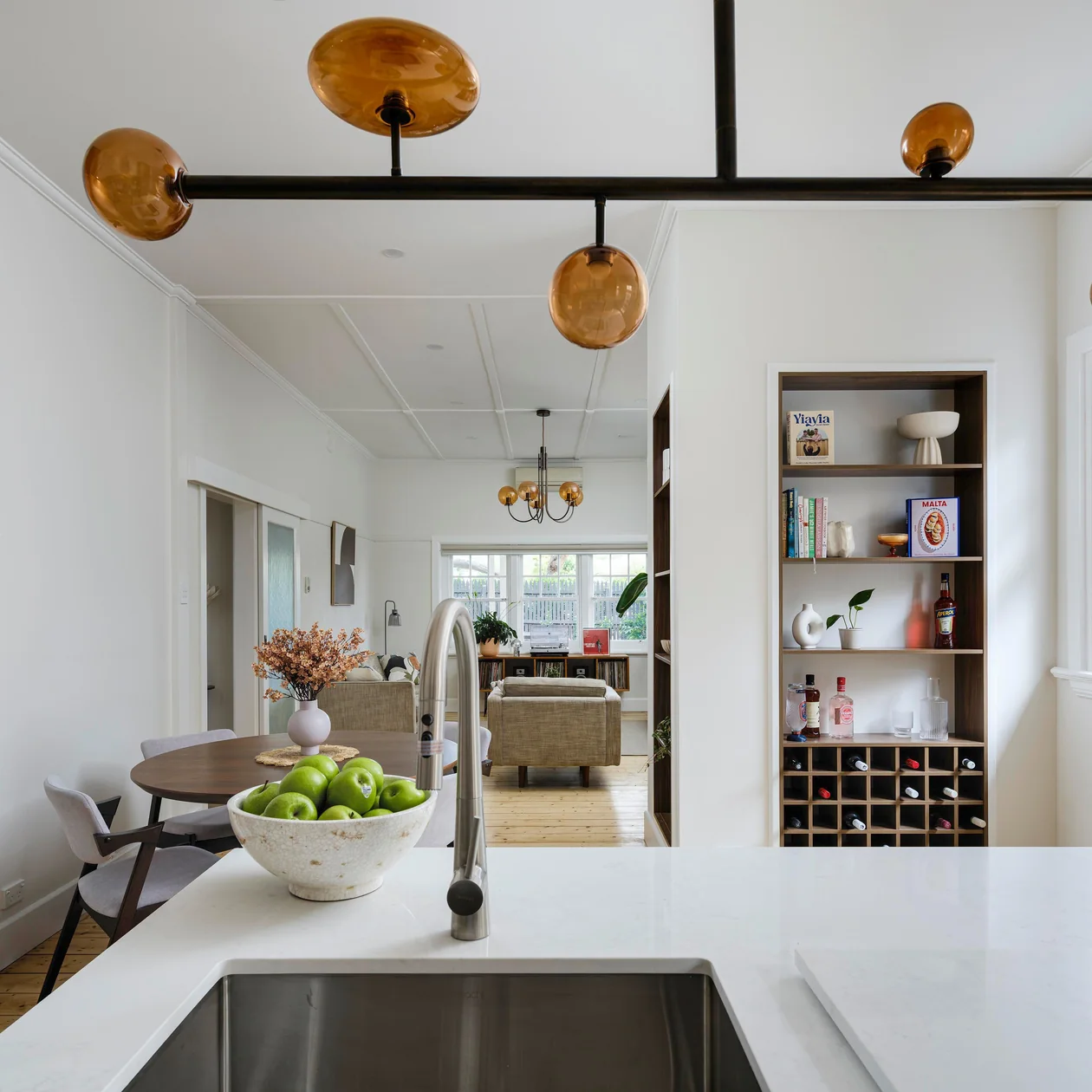 Amber glass pendant lights above a kitchen island with the dining and living area beyond