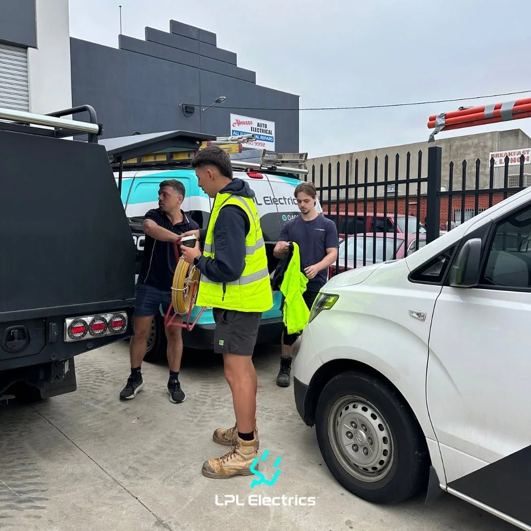Two LPL Electrics Group electricians in conversation beside their work vehicles