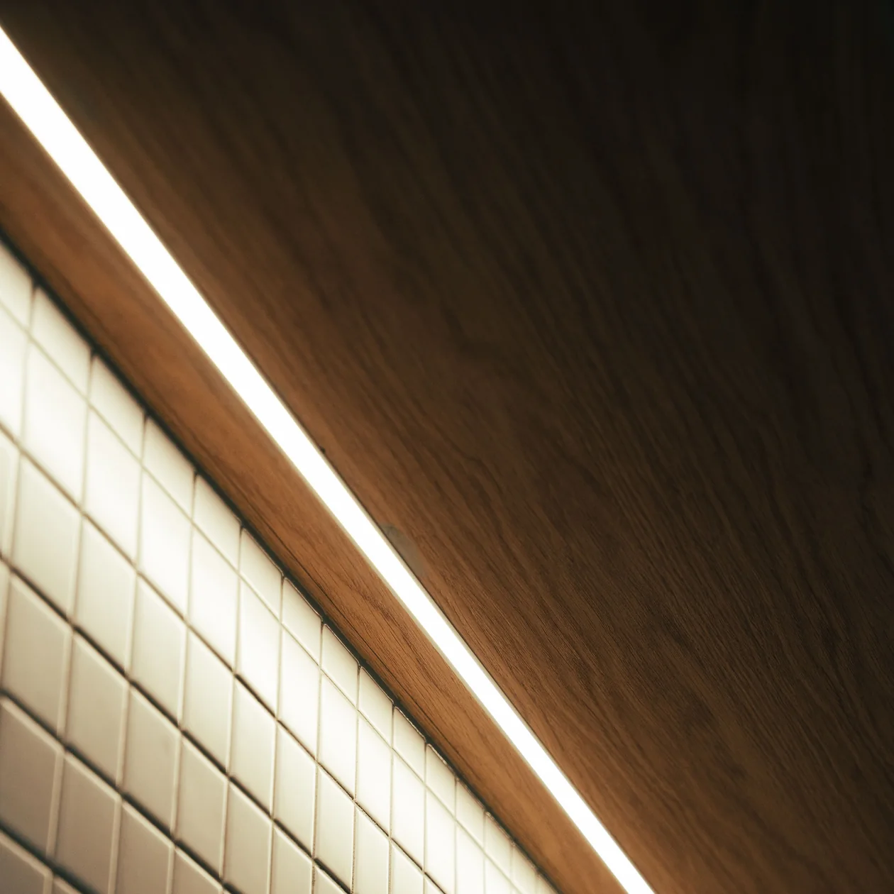 Recessed LED strip lighting running between a tiled wall and timber ceiling