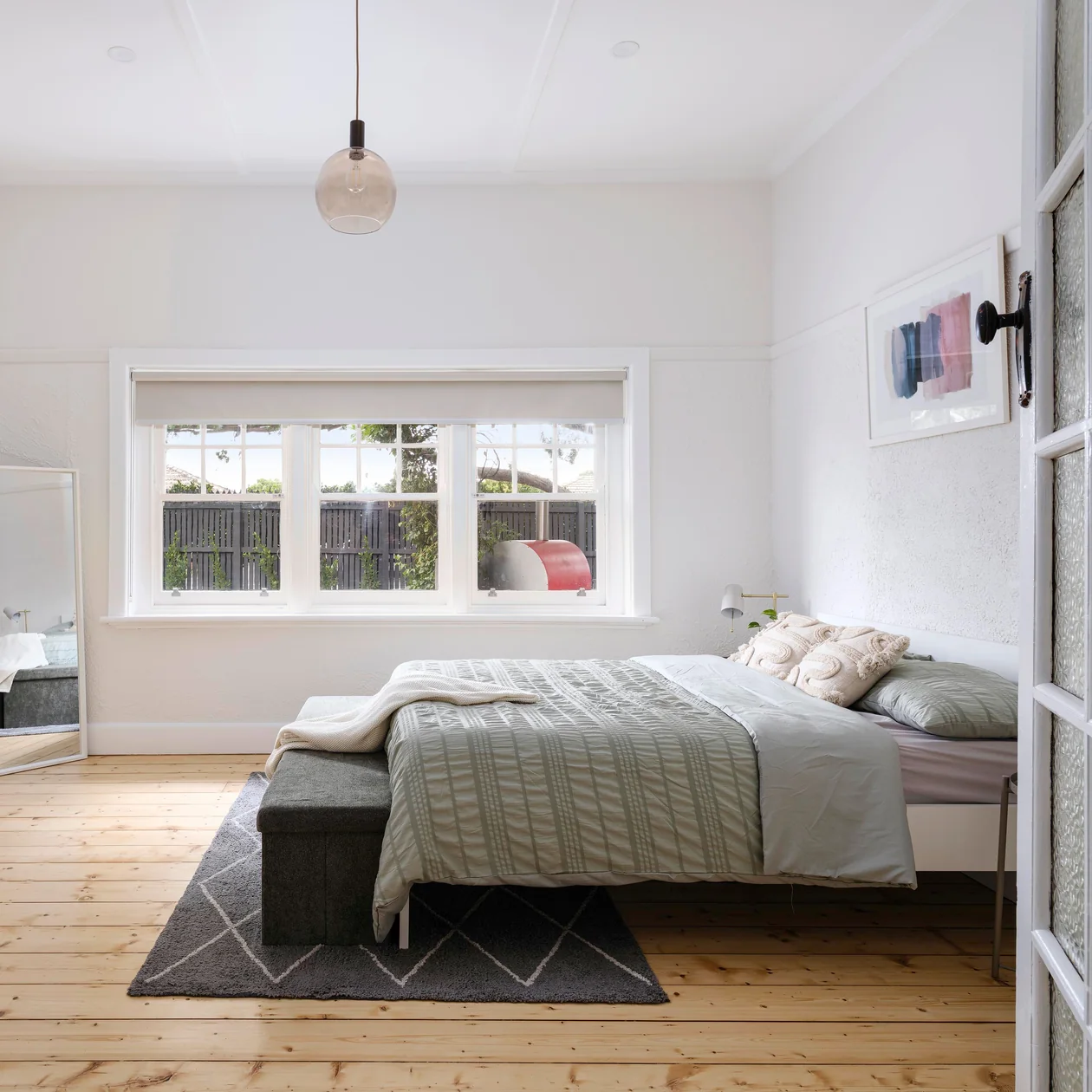 Renovated bedroom with a glass pendant light and timber floors
