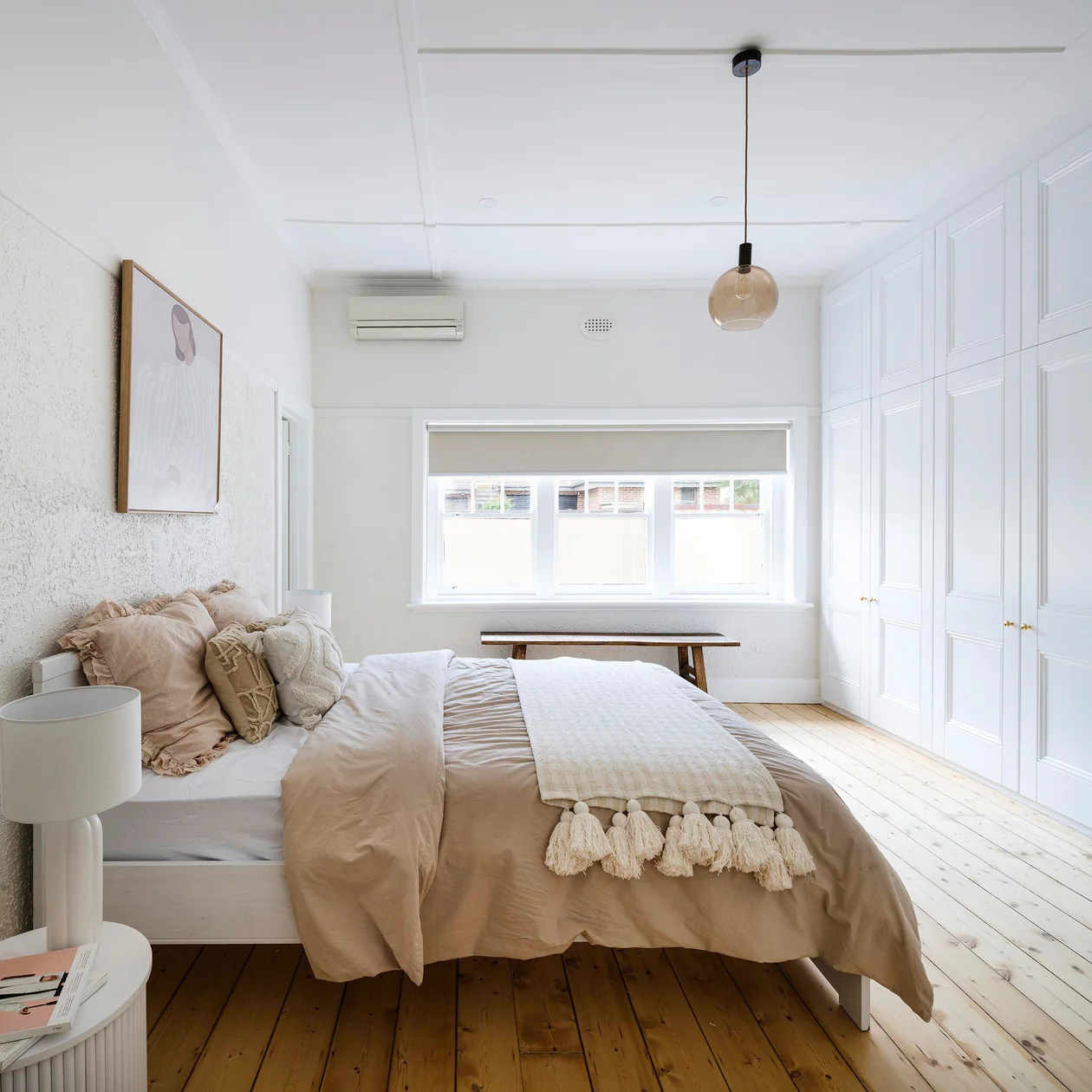 Bedroom with a smoked glass globe pendant hanging above timber floorboards
