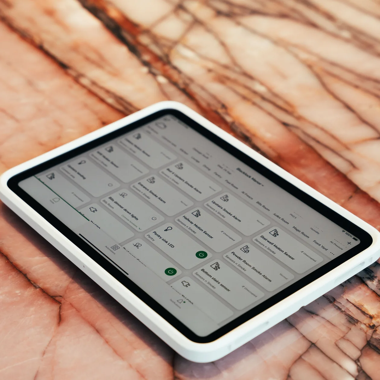 Smart home control tablet showing lighting and sensor controls on a marble benchtop