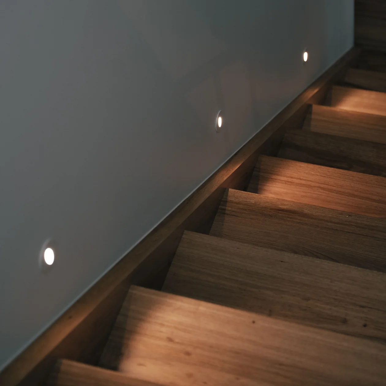 Step lights set into the wall along a timber staircase