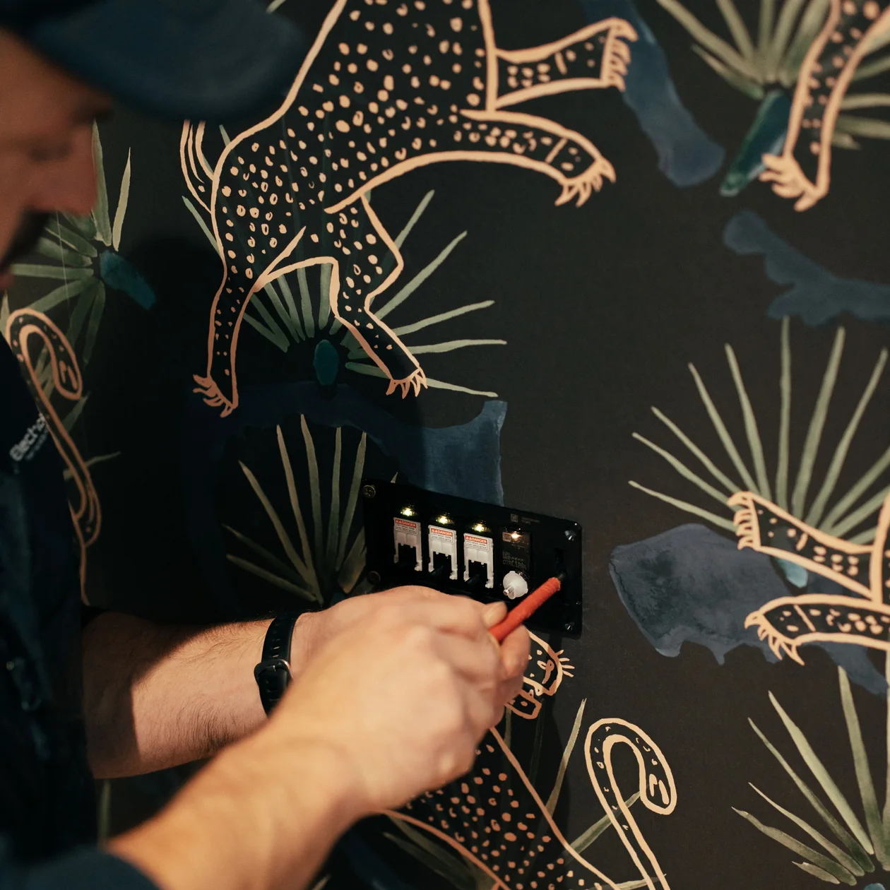 Electrician working on an illuminated switch plate on a patterned feature wall