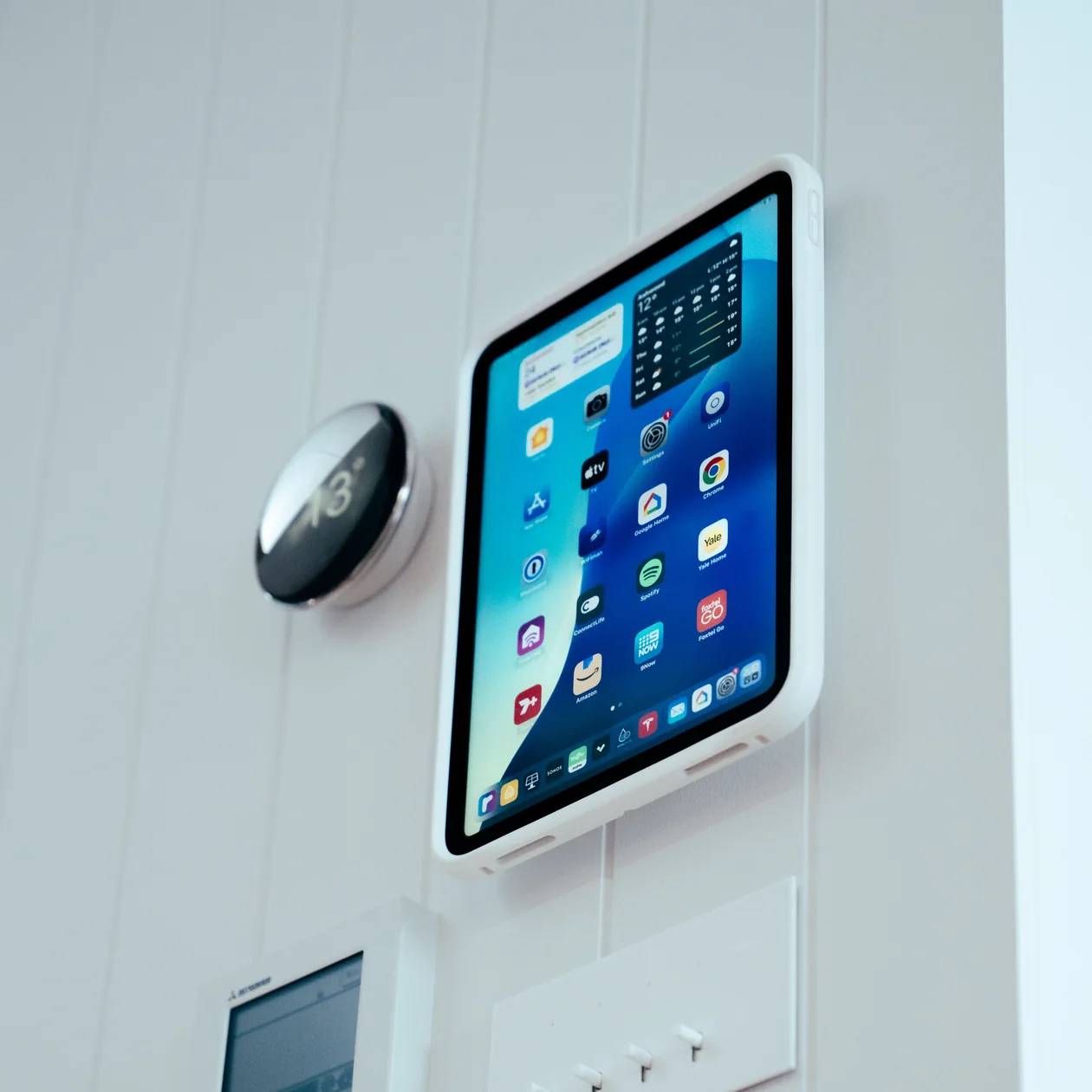 Wall-mounted tablet beside a smart home controller and switch plates